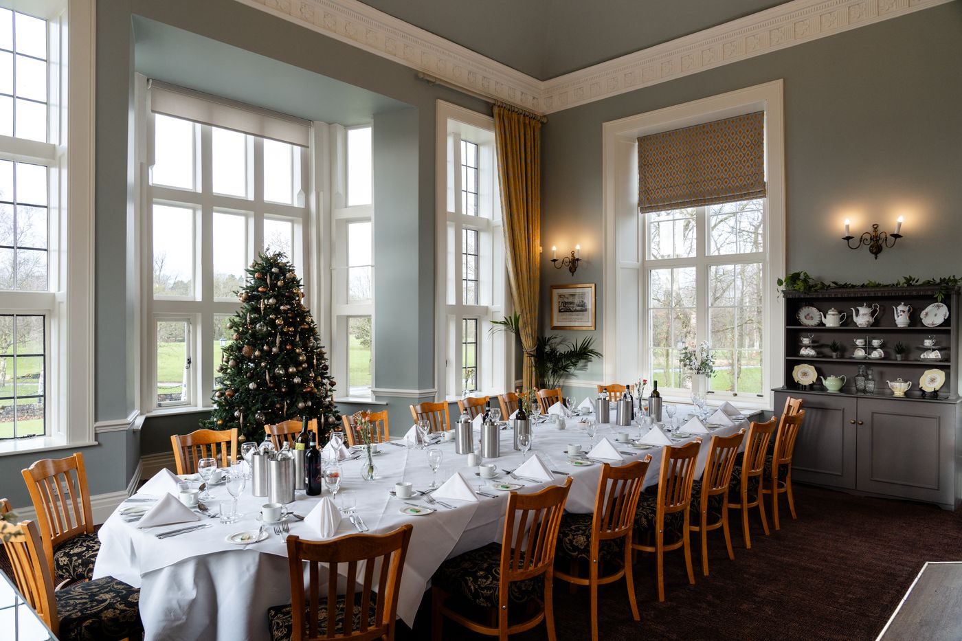 A long table laid for Christmas dinner beside a decorated tree