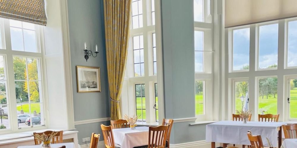 Tables laid in the Lounge beside its tall windows